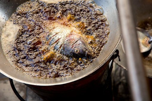 Fish in a pan with boiling oil at a street food stall in Bangkok, Thailand..