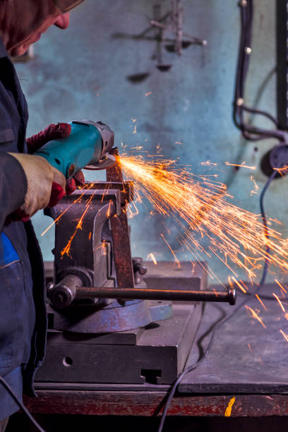 istock Metal Processing. Man Fitter in Protective Gloves and Uniform With Gringer Tool For Metal Work With Bunch of Sparks 1633890326