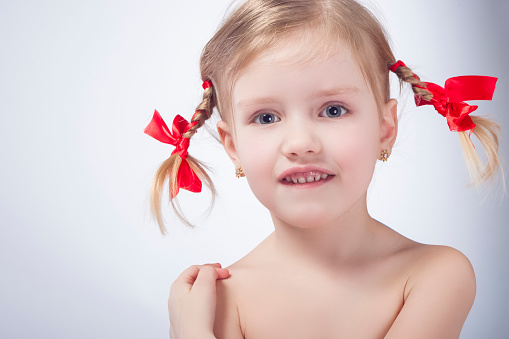 ittle Caucasian Girl Posing With Long Pigtails Against White Background. Horizontal Image