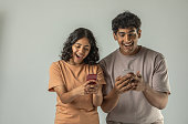 Siblings looking surprisingly at smart phones on white background