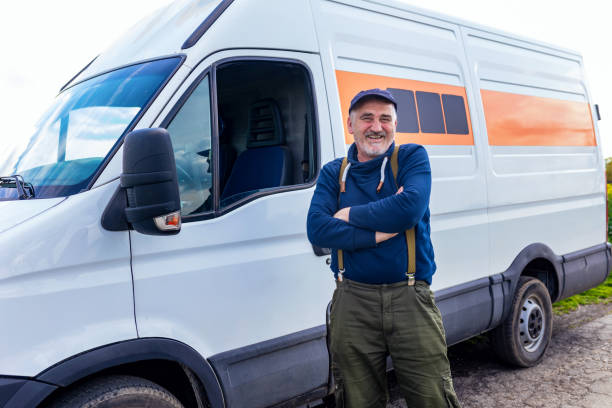 istock Happy confident male driver standing in front on his van and looking at camera. 1633947813
