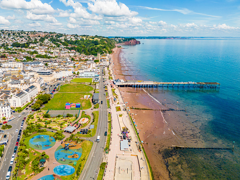 Teignmouth, UK. 16 August 2023. Aerial view of Mini-golf course at Teignmouth seafront with people on the beach and playing golf.