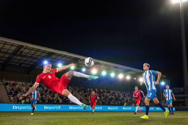 istock Young man kicking football mid-air 1633956965