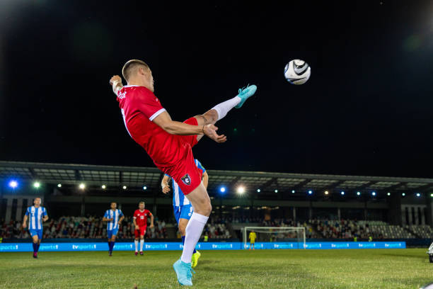 istock Young man kicking football mid-air 1633956967