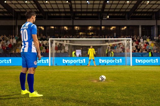 Young man getting ready for penalty kick during football match.