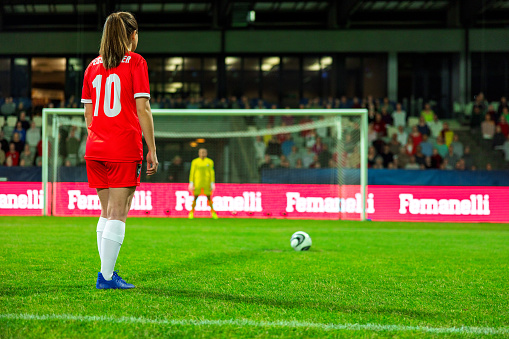 Young woman getting ready for penalty kick during football match.