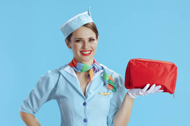 assistente di volo femminile moderna felice sul blu - segnale di uscita demergenza foto e immagini stock