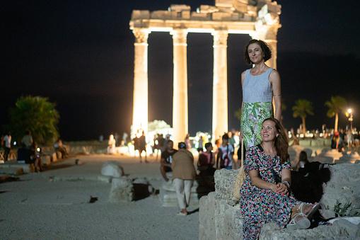 Two woman tourist in Side Apollon temple at night.