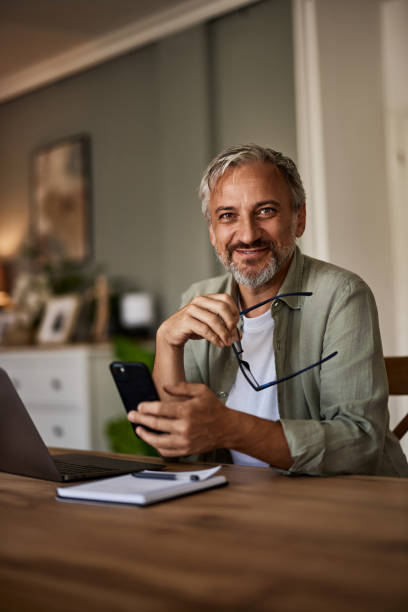 istock Portrait of a handsome smiling senior man using a smartphone, looking at a camera. 1633957963