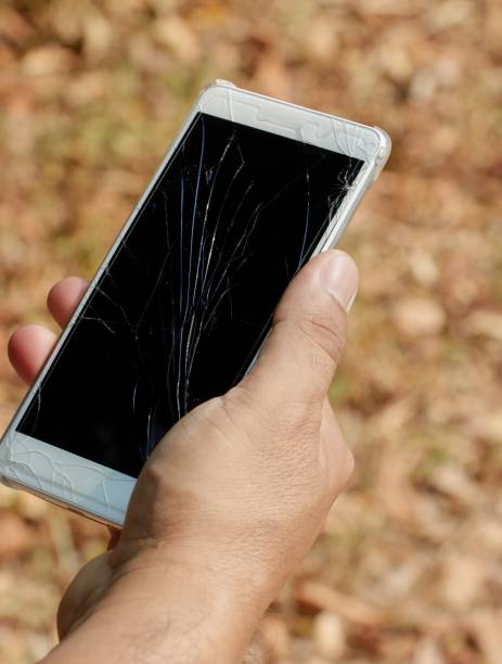 Cropped view hand holding a smartphone with broken screen stock photo