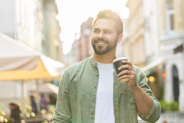 istock Young man guy enjoying drinking morning coffee hot drink, relaxing, taking a break in city street 1633993620