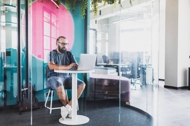 Adult man coding on laptop at creative coworking office