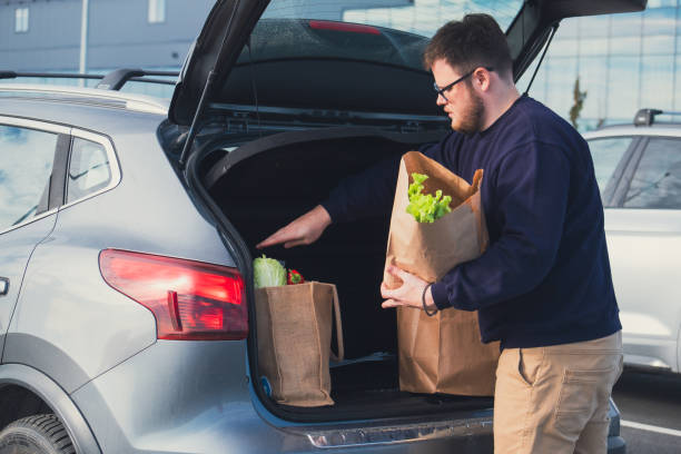 istock happy man put groceries bag in car trunk 1634006555