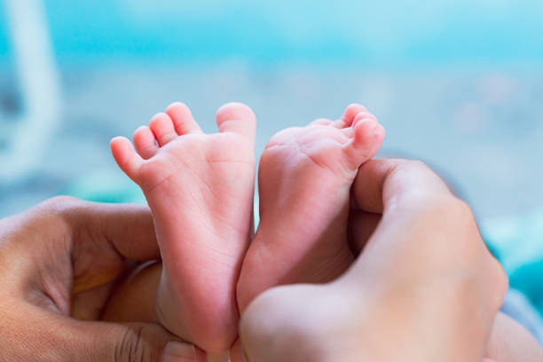 piedi del bambino, piedi del bambino nelle mani, piccoli piedi del bambino appena nato sulle mani, ritratto femminile in primo piano, madre e il suo bambino, concetto di famiglia felice, bella immagine di concezione del parto. - human pregnancy massaging midwife prenatal care foto e immagini stock