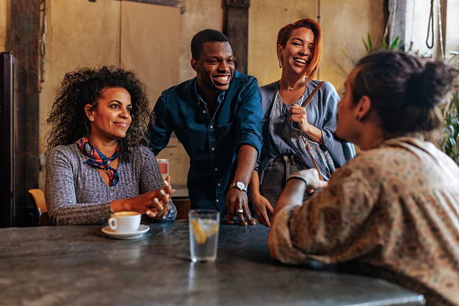 Four young multiracial people having a conversation while meeting in the restaurant