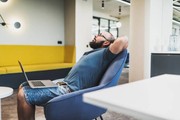 Tired mature beard man relaxing at coworking stock photo