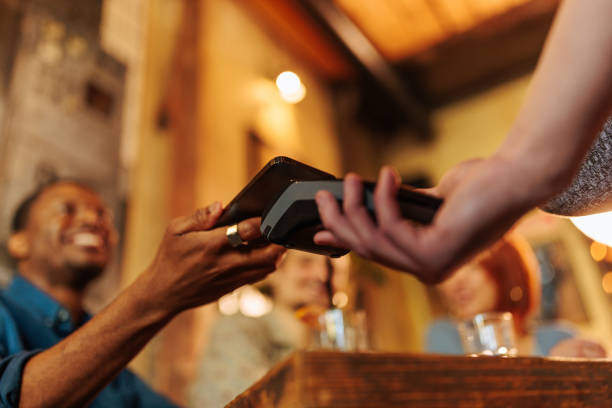istock African-American man paying with phone in restaurant. 1634037878