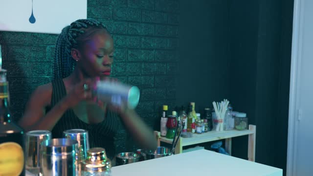 Black waitress prepares a cocktail on the bar of a pub
