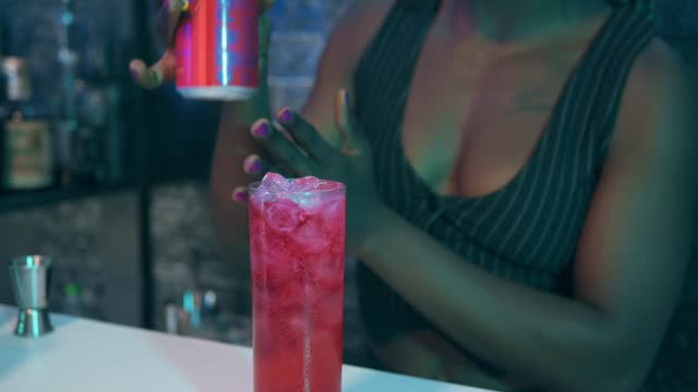 Waitress prepares a cocktail and pours a soft drink into the glass