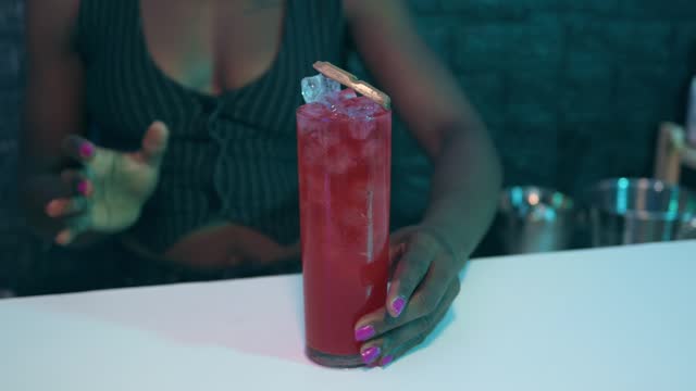 Black waitress prepares a cocktail on the bar of a pub