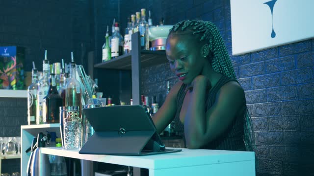 Black waitress looking a digital tablet at a pub bar. Small owner business