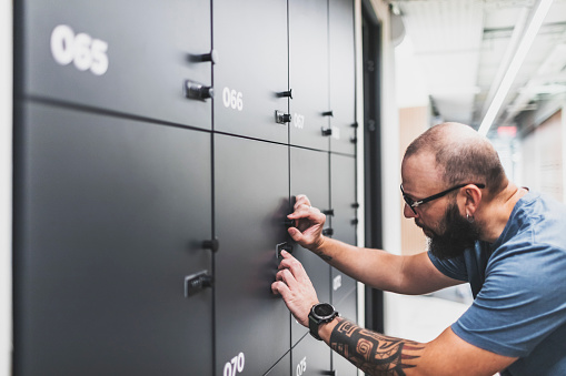 Adult man opening his locker at modern coworking