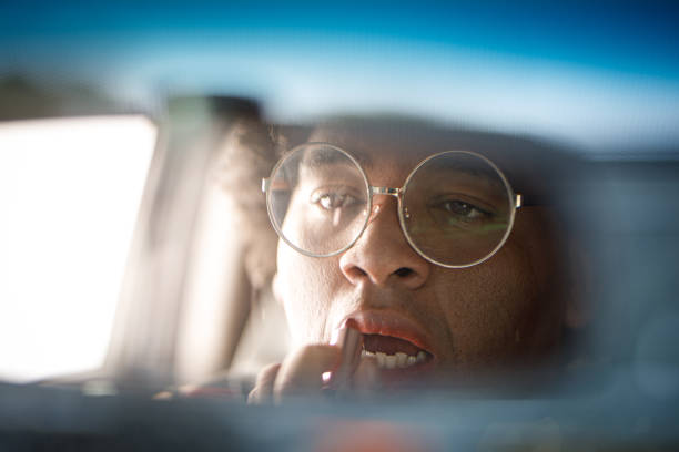 istock Woman applying lipstick using the interior rear view mirror 1634059165