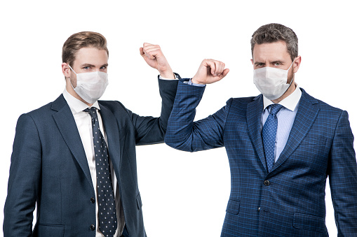 social distancing during coronavirus. boss and employee in medical mask. covid19 prevention. successful deal of men partners. business colleague bumping elbows. businessmen not shaking hands.