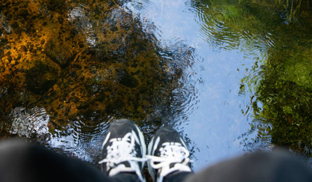 istock Women's legs hang over the river. 1634083055
