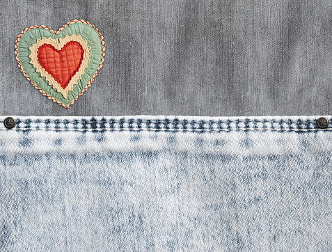 Grey and light grey  denim background with a seam and felt heart. Light gray color denim jeans fabric texture. Valentine's day denim backdrop. Copy space for text