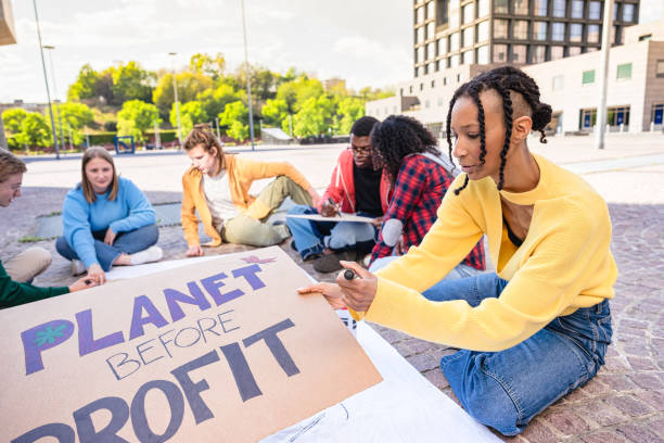 Young activist people making a banner eco-themed slogans to participate at flash mob for environmental protection.