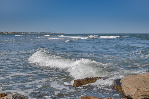 Sea waves rolling on the shore. The blue color of the sky is reflected in the water of the sea.