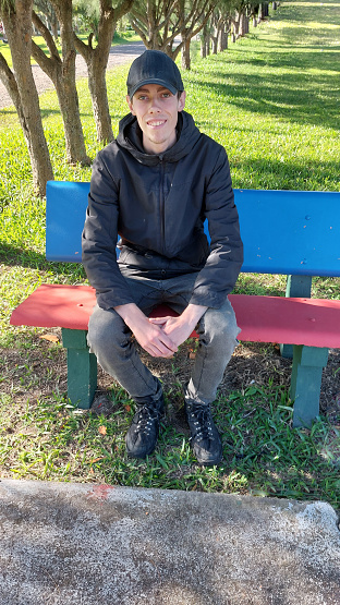 Young man sitting on a bench in the park