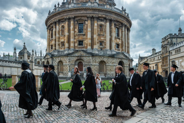 Oxford University England UK Graduation Ceremony Students walk past Radcliffe Camera during the Graduation Ceremony in Oxford, England, UK on a cloudy day. radcliffe camera stock pictures, royalty-free photos & images