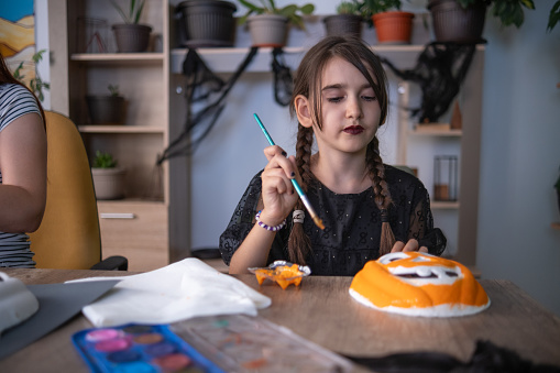 One little girl painting a pumpkin mask she will use for Trick-or-treat