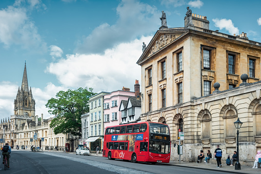 People wait for bus on High Street in downtown Oxford, England, UK on a cloudy day.