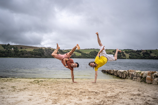 Portrait of friends doing handstand on the beach