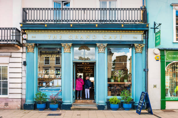 People stand at the entrance of a coffee shop in central Oxford, England, UK on a cloudy day.