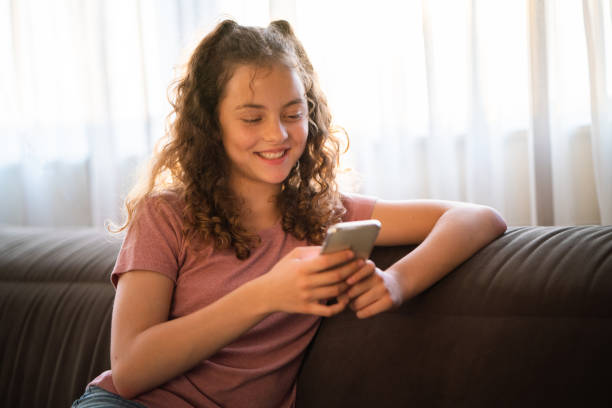 istock Girl using mobile phone on sofa at home 1634189761