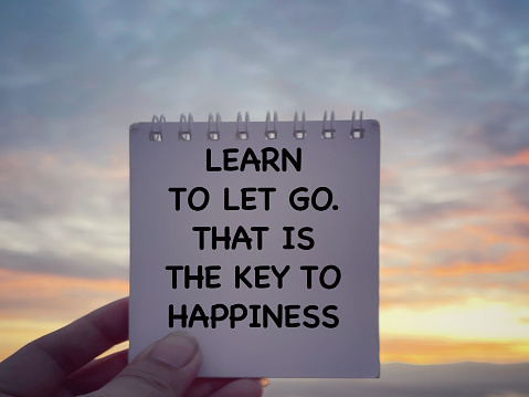 Learn To Let Go. That Is The Key To Happiness written on a notepad. With blurred styled background.