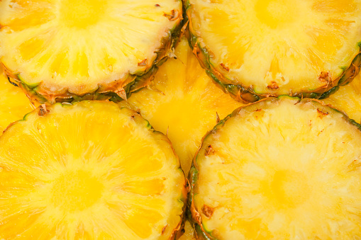 Pineapple juicy yellow slices as a background. Top view.