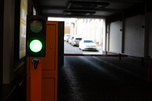 The green traffic light is on at the entrance to the parking lot with a barrier in a dark tunnel