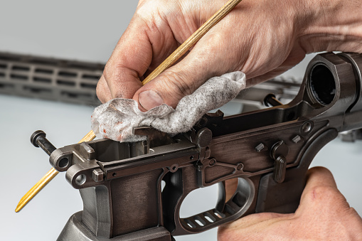 Man`s dirty hands holding rifle parts details and cleaning the gun