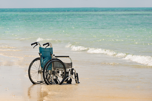 Empty wheelchair stands on the seashore calm sea Concept freedom