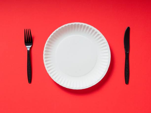 istock A white paper plate with black plastic utensils on a red background 1634294352