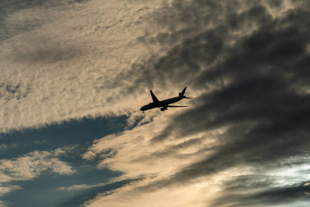 istock Jet plane small silhouette arrive from travel, sunset evening clouds. Big passenger airplane crossing the sky. 1634314015