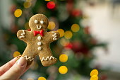 Christmas gingerbread cookie man in front of Christmas tree with blurred background