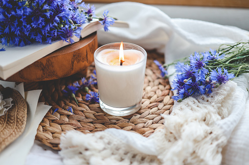 Burning candle, book and cornflowers, aesthetic summer photo.