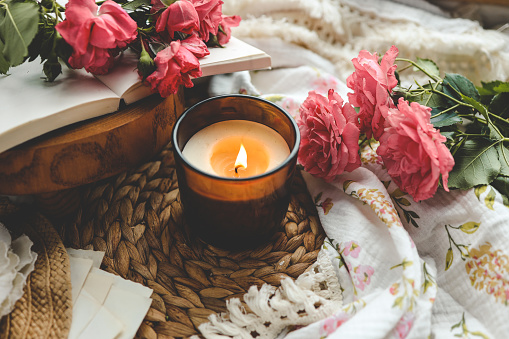 Burning candle, book and roses, aesthetic summer photo.