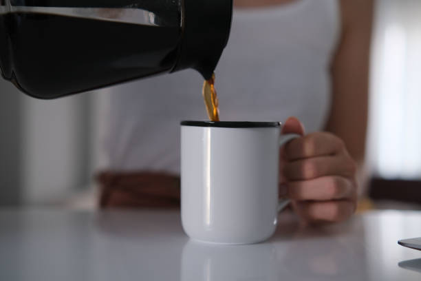 A close-up of a mid-adult Caucasian woman pouring coffee into a glass, before going to exercise.